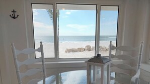 Une chambre avec vue sur la plage, une chaise blanche, une petite table et une lanterne.