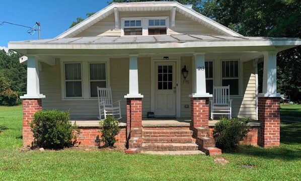 A single-story house with a porch, a front door, and a mailbox.