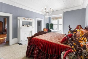 Ein Schlafzimmer mit einem großen Bett, einem weißen Kamin und einer Kronleuchter.