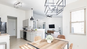 Una cocina moderna con comedor, que incluye una mesa de madera, sillas y un ventilador de techo.