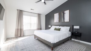Un dormitorio moderno con una cama grande, un ventilador de techo y dos lámparas de noche.