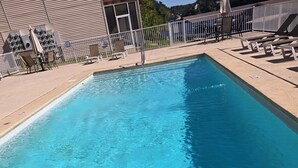 Una piscina rectangular con agua azul cristalina, rodeada por un solárium con baldosas y tumbonas.