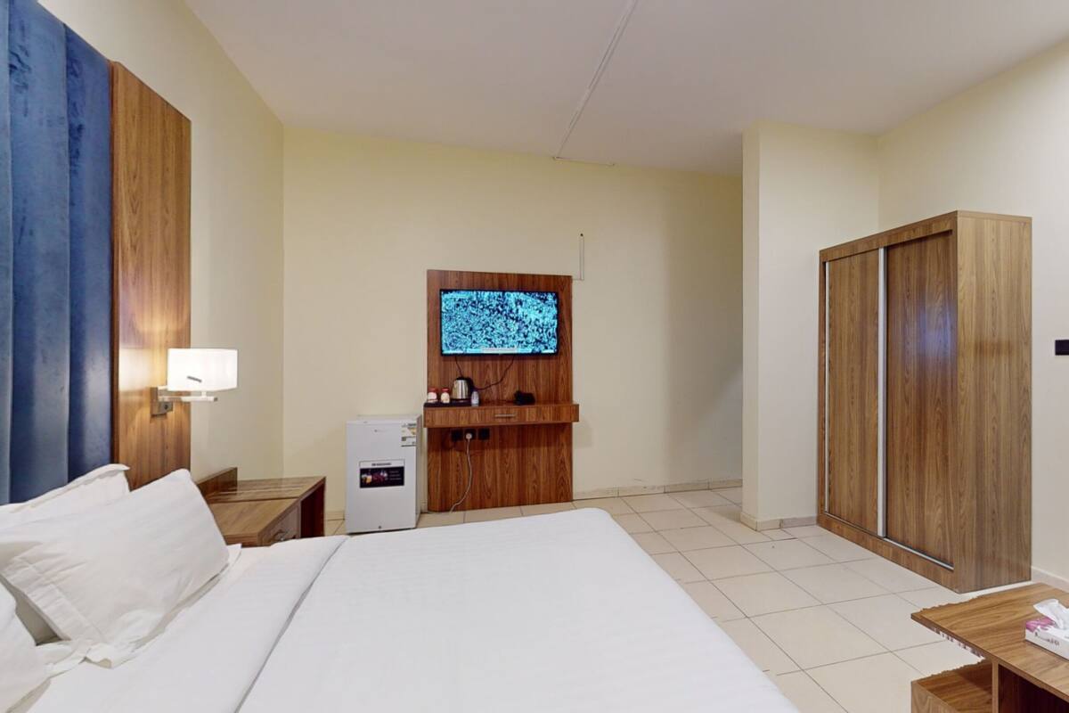 A hotel room with a bed, a desk, a TV, a wardrobe, and a mirror.