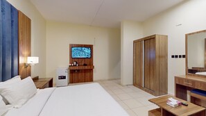A hotel room with a bed, a desk, a TV, a wardrobe, and a mirror.