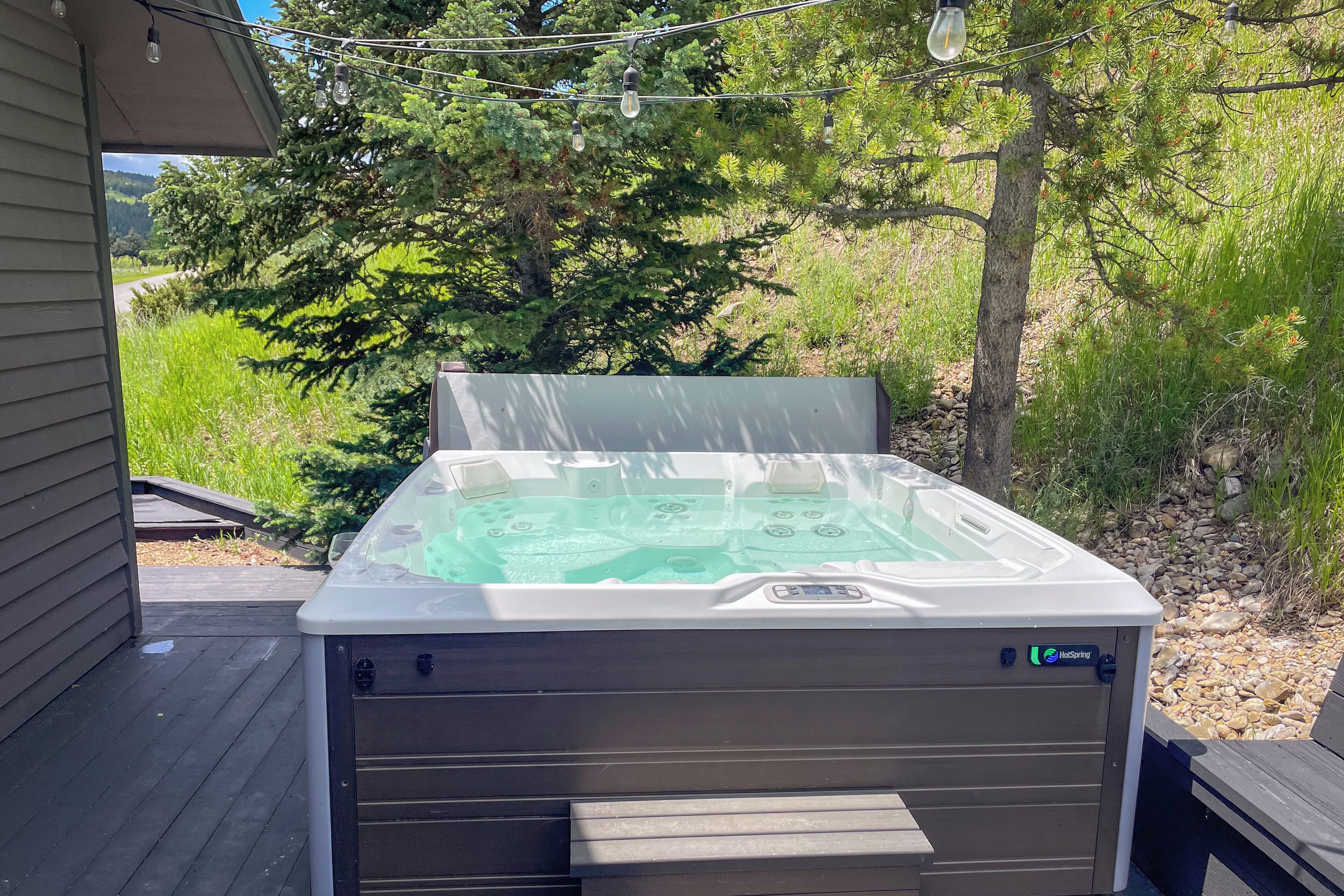 A hot tub on a wooden deck with a view of a forested area.