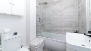 A modern bathroom with a glass-enclosed shower, a white sink, and a toilet. - 
Stylish Apartment Close to Fulham Palace (London)