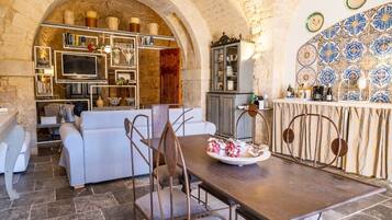 A cozy dining area with a stone archway, a white sofa, and a wooden table with chairs.