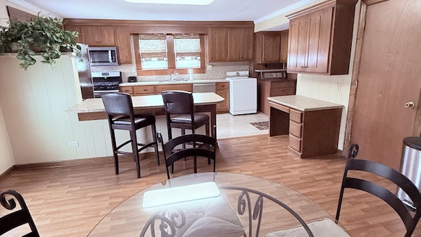 A modern kitchen with wooden cabinets, a dining area with a glass table and chairs, and a ceiling fan. - Downtown Convenience near Lake Norman (Mooresville)
