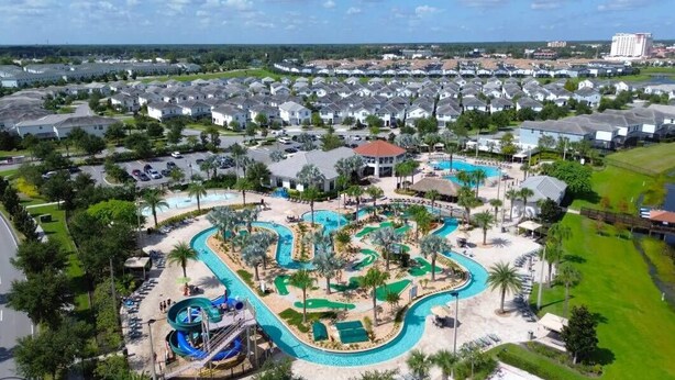 A residential area with a large swimming pool, a water slide, and a small building with a red roof.