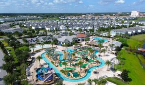A residential area with a large swimming pool, a water slide, and a small building with a red roof.