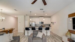 A modern living room with a grey sofa, a wooden coffee table, and a dining area with a wooden table and chairs.