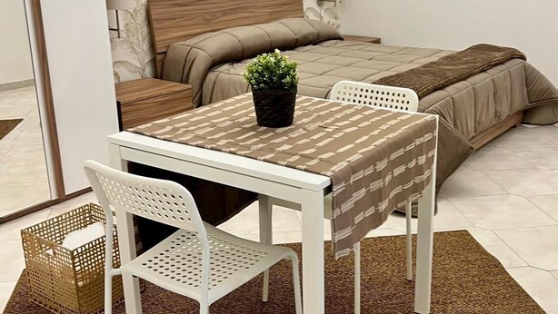 Ein Schlafzimmer mit Bett, Nachttisch, Lampe und einer Wand mit gerahmten Bildern.