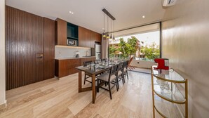 Una cocina moderna con armarios de madera, un comedor con mesa de vidrio y vistas al exterior.