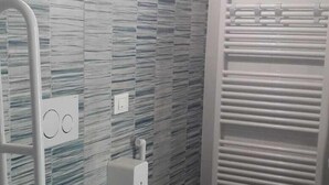 Een badkamer met een modern design, met een toilet, douchegedeelte en een handdoekrek.