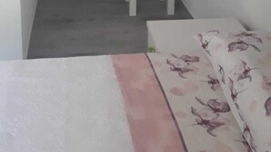 Een kleine, compacte kamer met een inbouwkast, een tafeltje en een bankje.