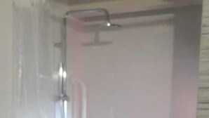 Een kleine, afgesloten badkamer met een douche, toilet en wastafel.