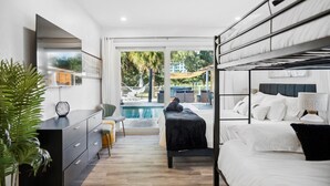 Un dormitori modern amb vista a la piscina, un llit negre i un panell cefalràix gris.
