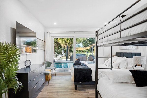 A modern bedroom with a pool view, a black bed, and a grey headboard.