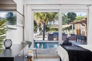 A bedroom with a view of a pool, outdoor seating, and a pergola.