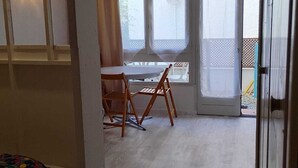 A room with a wooden table and chairs, a window with a view, and a door leading outside. - 
500 m beach studio cabin in residence Cap Atlantic, St Palais/mer swimming pool (Saint-Palais-sur-Mer)