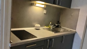 A compact kitchen with a single countertop, a built-in stove, a sink, and a small storage cabinet. - 
500 m beach studio cabin in residence Cap Atlantic, St Palais/mer swimming pool (Saint-Palais-sur-Mer)