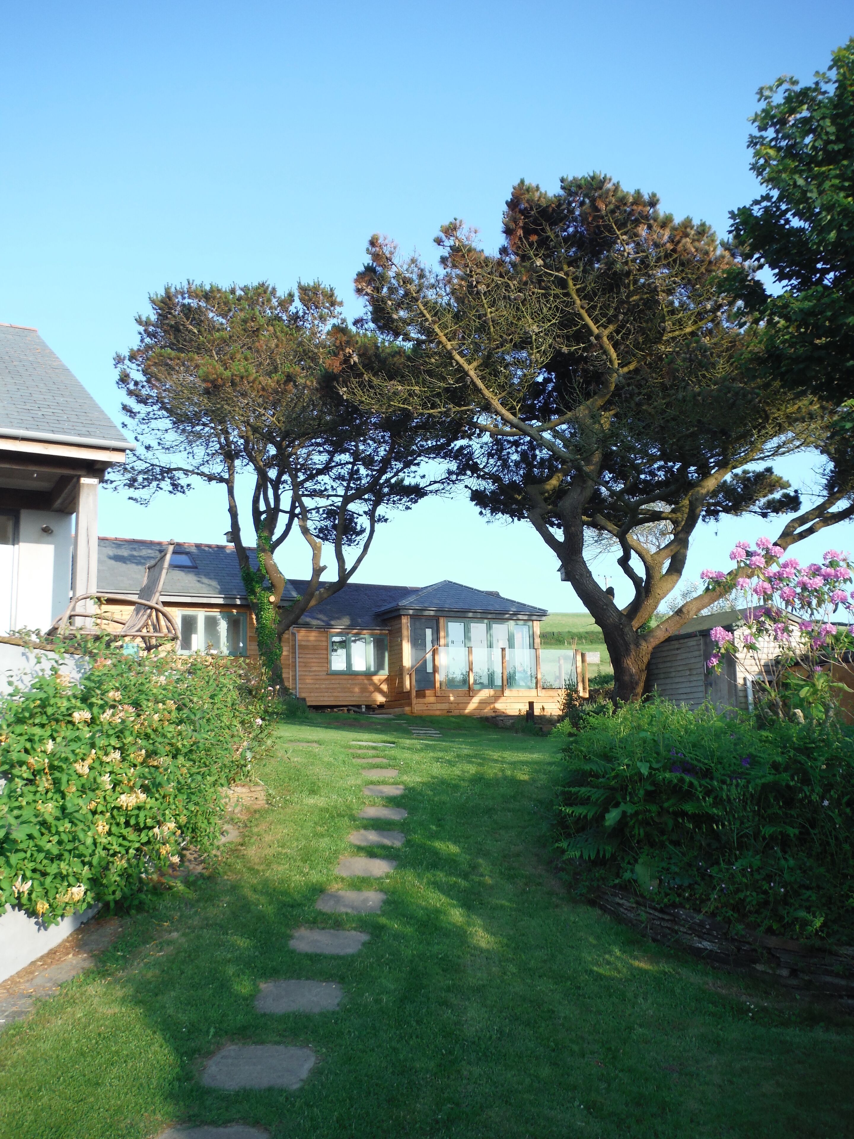 A residential property with a well-maintained lawn, a stone pathway, and a large tree.
