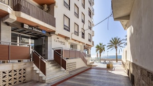 Een hotelentree met een trap naar de begane grond, een palmboom en uitzicht op zee.