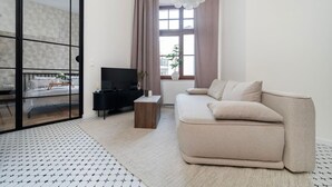 A modern living room with a sofa, TV, and a sliding glass door leading to a balcony.