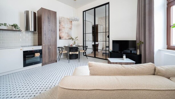 A modern living space with a kitchen, dining area, and a seating area with a sofa.