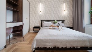 A modern bedroom with a large bed, a desk, and a chair. There are two bedside tables with lamps.