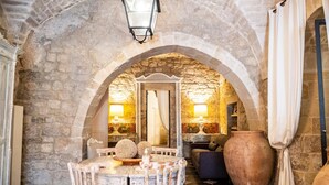 Une pièce aux murs de pierre, avec une table ronde, des chaises, un canapé et un grand vase.