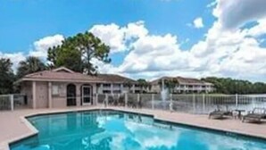 A swimming pool with a clear blue sky and a few clouds in the background. - Spacious 3-bedroom first floor coach home with attached garage in North Naples (Naples)