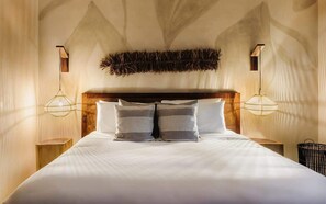 Una cama con cabecera de madera, dos mesitas de noche y un adorno en la pared.