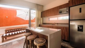 Cozinha moderna com ilha central, banquetas de madeira, um banco e uma janela grande com guarda-sol.