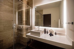 A modern bathroom with a glass-enclosed shower, a large mirror, and a white vanity with two sinks. - Anaya Luxury Jungle View Penthouse Rooftop Pool (Tulum)