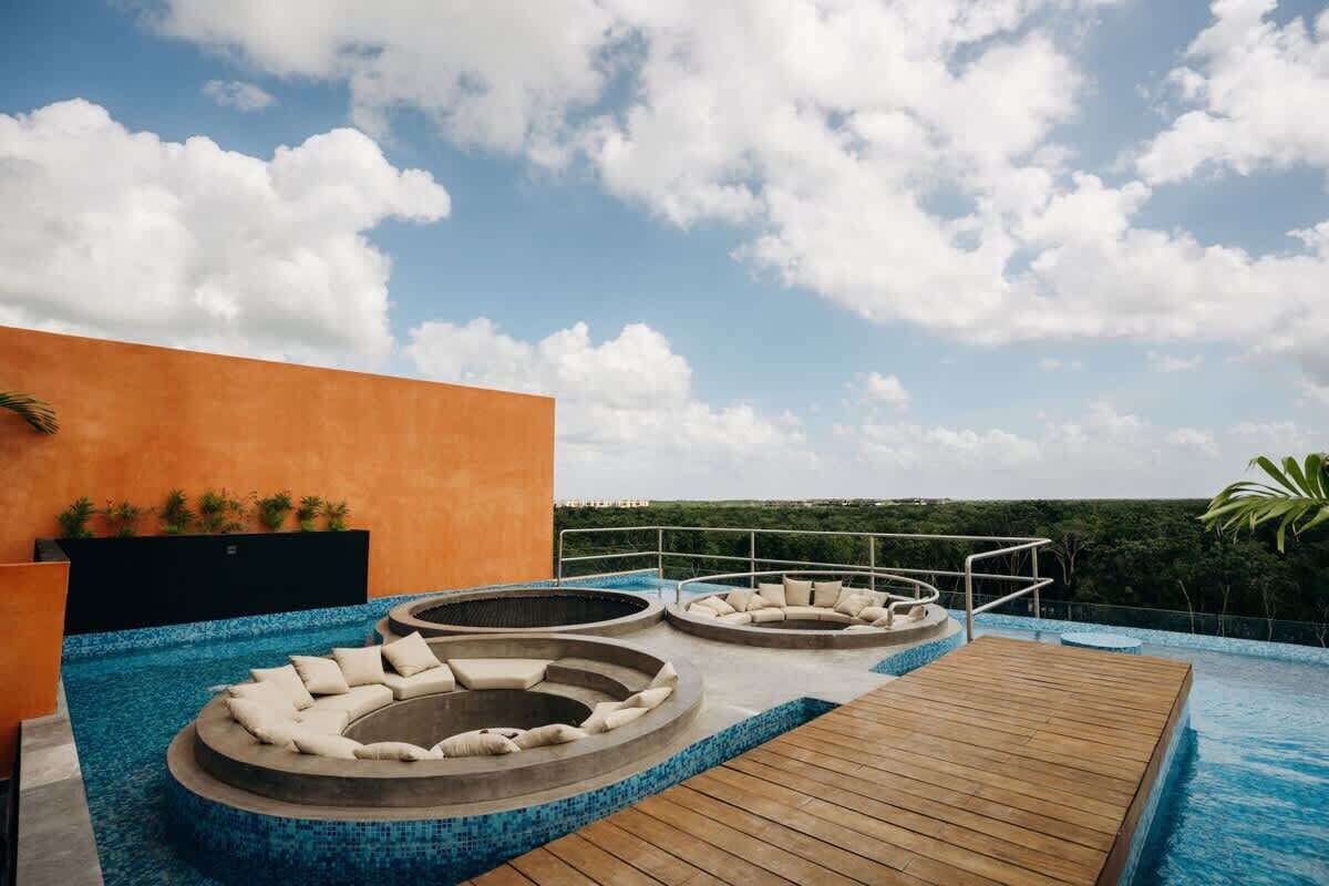 A rooftop infinity pool with a wooden deck and two hot tubs.