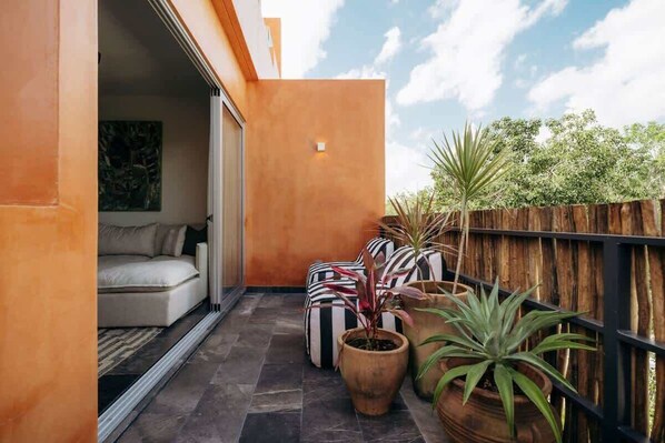 A balcony with a sofa, striped cushions, and potted plants.