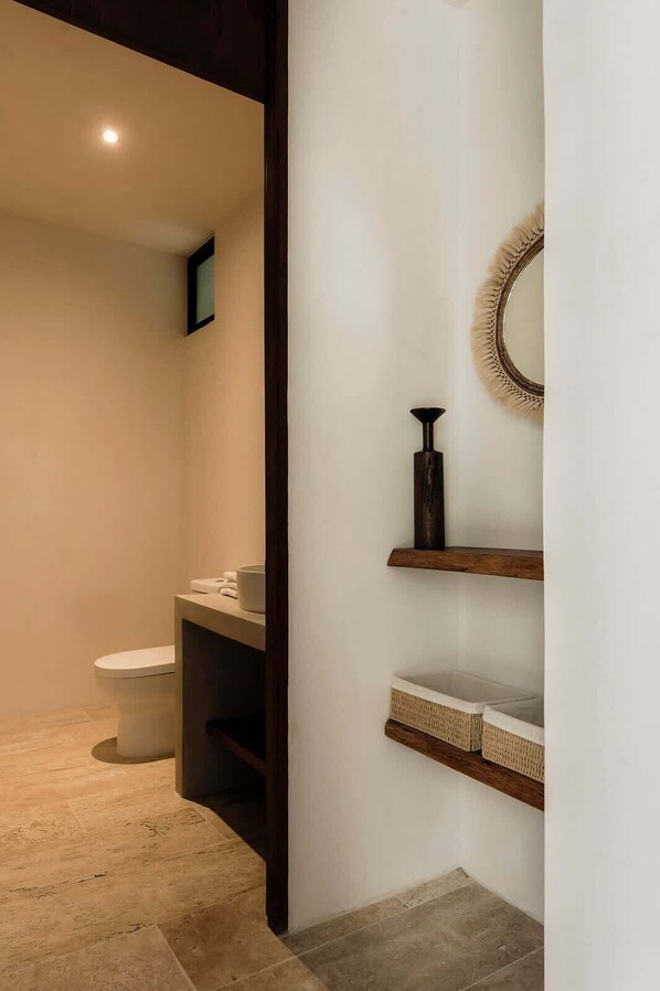 Ein Badezimmer mit Toilette, Spiegel und Regalen.