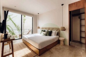 Ein Schlafzimmer mit Bett, Nachttischen, einem Kleiderschrank und Blick auf Grünflächen.