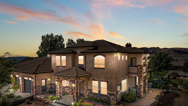 A two-story house with a stone facade, multiple windows, and a landscaped front yard.