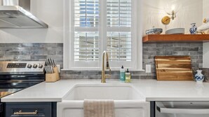 A modern kitchen with a white countertop, stainless steel appliances, and a window with blinds. - Palazzo Sul Monte-Due (Wilmington)