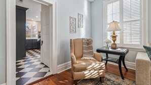 A living room with a beige armchair, a patterned rug, and a table with a lamp. - Palazzo Sul Monte-Due (Wilmington)