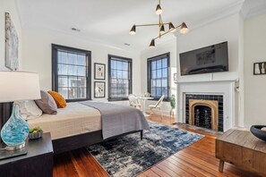A modern bedroom with a large bed, a fireplace, and multiple windows.