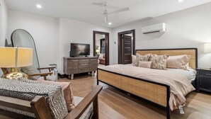 Quarto com cama, televisão, cómoda e ventoinha no teto.