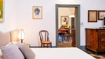 Ein Schlafzimmer mit einem Bett, einem Sessel, einer Lampe und einem Schminktisch.
