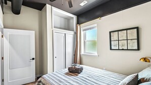 Quarto com cama, janela, porta e ventilador de teto.