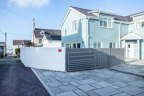 A residential building with a gated entrance, a driveway, and a clear sky.