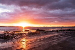 A sunset over a beach with a road leading to the water.