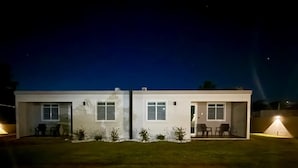 Uma casa moderna de dois andares com telhado plano, janelas amplas e uma pequena varanda.