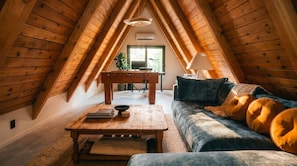 An attic room with a wooden table, sofa, and lamp.